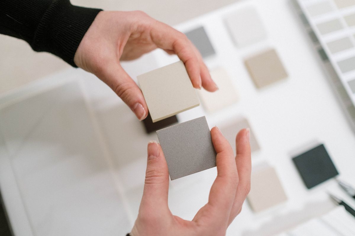 Hands comparing neutral colour samples