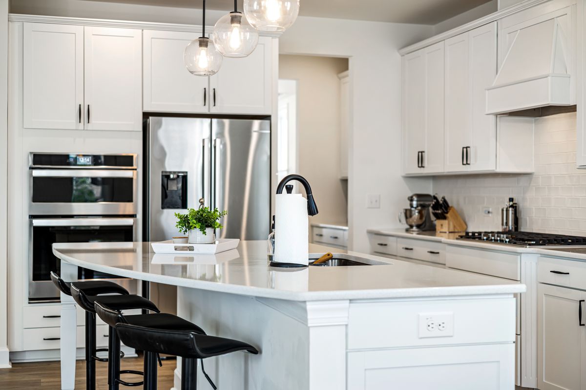 A white modular kitchen with an island and pendant lights