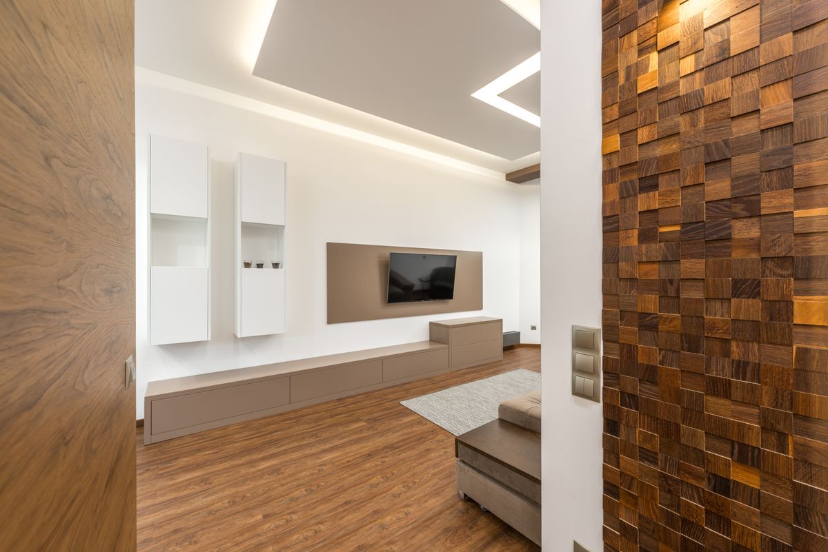 A living room with a white wall unit and a wooden feature wall
