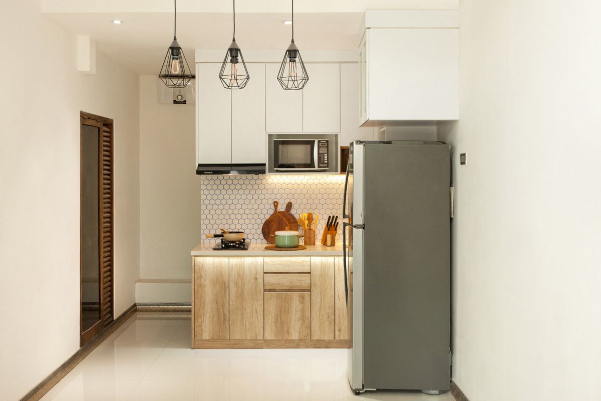 A compact apartment kitchen with oak fronts and a tall fridge unit