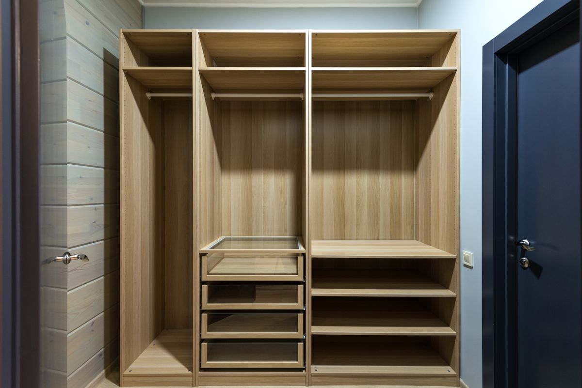 An open light-oak wardrobe with shelves, rails and drawers