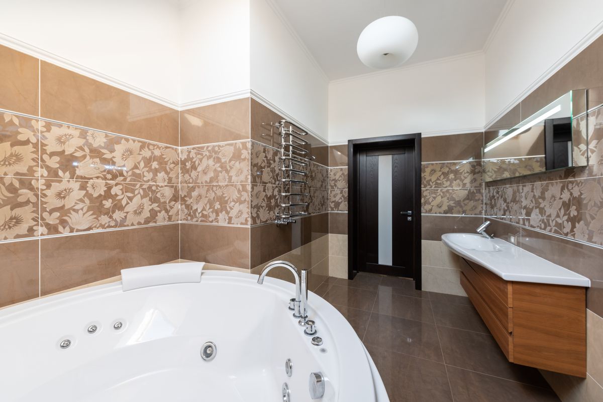 A bathroom with a wooden vanity, a bath and patterned tiles