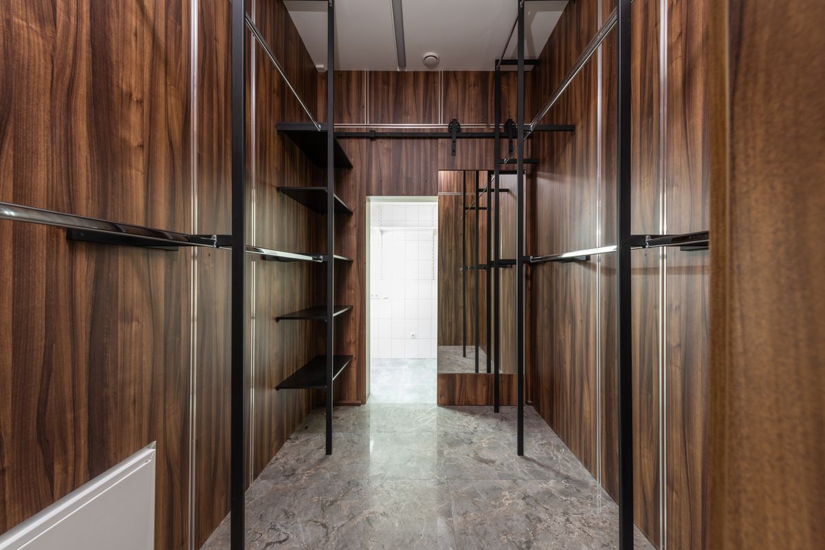 A walk-in wardrobe with wooden panelling and open shelving